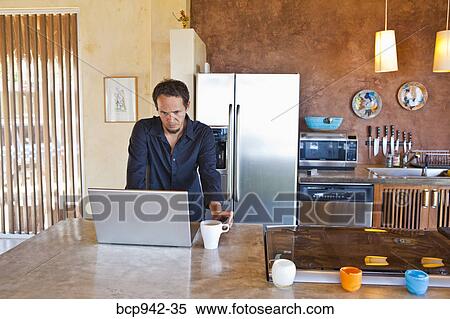 man working on laptop in kitchen View Large Photo Image Stock Photography - man working on laptop in kitchen. Fotosearch