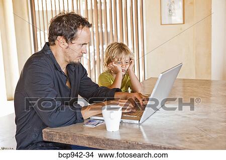Picture - man working on laptop next to child. Fotosearch