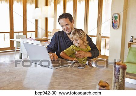 Stock Image - man working on laptop with child on lap. Fotosearch
