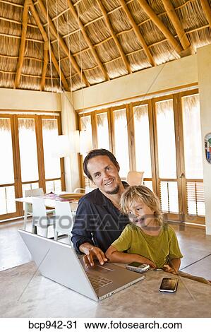 Stock Image - man working on laptop with child on lap. Fotosearch