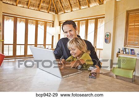 man working on laptop with child on lap View Large Photo Image Stock Photo - man working on laptop with child on lap. Fotosearch