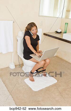 Stock Image - woman on laptop in bathroom. Fotosearch