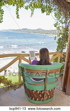 woman reading e-book on balcony View Large Photo Image Stock Image - woman reading e-book on balcony. Fotosearch