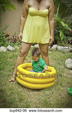 Stock Photograph - woman with young boy playing in pool. Fotosearch