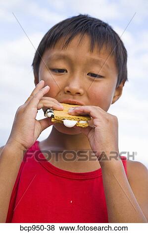 Stock Photo - boy eating s'more outdoors. Fotosearch
