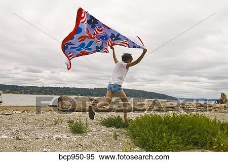 Stock Photography - boy running on beach with flying towel. Fotosearch
