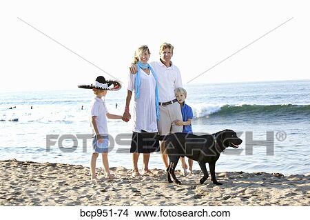 Picture - family walking on beach with dogs. Fotosearch