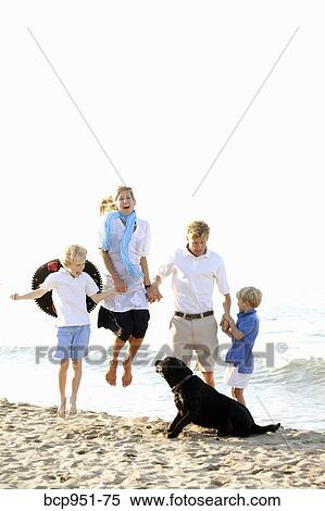 Stock Photography - family walking on beach with dogs. Fotosearch