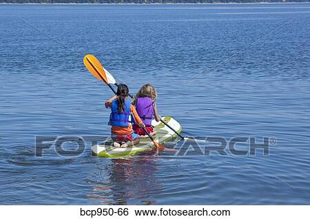 Stock Photograph - girls on paddle board in lake. Fotosearch