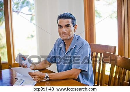 Stock Image - man at table with bills. Fotosearch