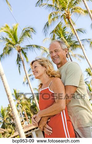 Stock Photo - middle aged couple with palm trees. Fotosearch