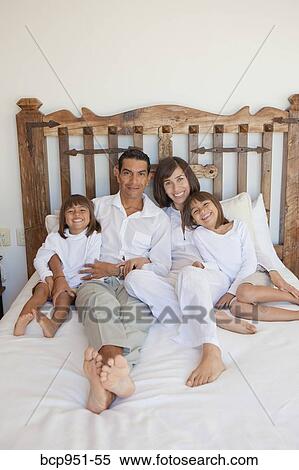 Stock Photography - parents and two daughters on bed. Fotosearch