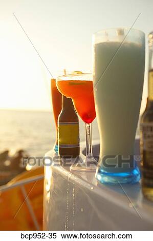 Stock Photography - row of cocktails on boat rail. Fotosearch