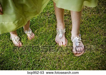 Stock Image - two pairs of feet in silver sandals. Fotosearch