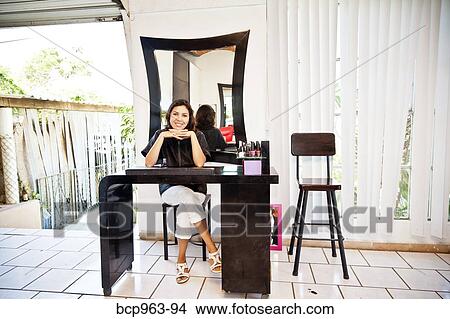 Picture - Beautician seated at manicure table in beauty salon. Fotosearch