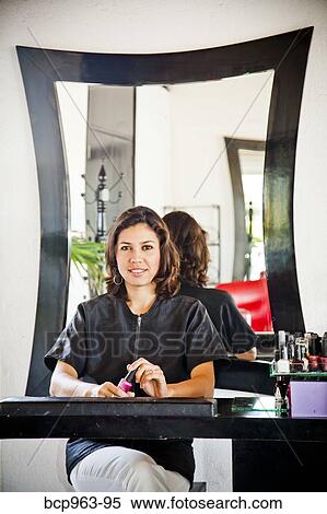 Beautician seated at manicure table in beauty salon View Large Photo Image Stock Photography - Beautician seated at manicure table in beauty salon. Fotosearch