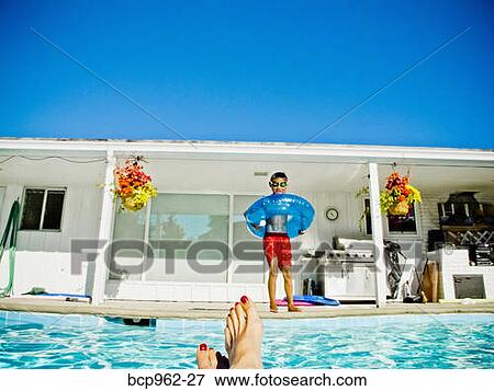 Stock Photo - Boy in floaty standing next to pool. Fotosearch