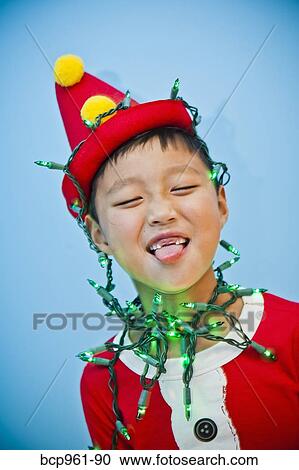 Stock Image - Boy in red costume with holiday lights. Fotosearch