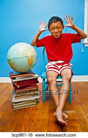 Boy making face next to books and globe View Large Photo Image Stock Photograph - Boy making face next to books and globe. Fotosearch