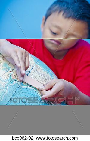 Stock Image - Boy placing bandaid on globe. Fotosearch