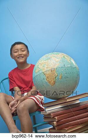 Boy seated near globe on top of books View Large Photo Image Picture - Boy seated near globe on top of books. Fotosearch