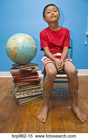 Stock Photography - Boy seated near globe on top of books. Fotosearch