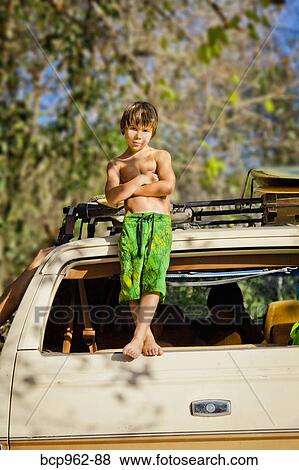 Stock Photo - Boy standing on back of car. Fotosearch