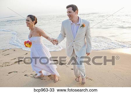 Stock Image - Bridal couple laughing on beach. Fotosearch