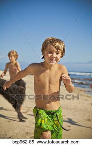 Stock Photography - Children running on beach with dog. Fotosearch