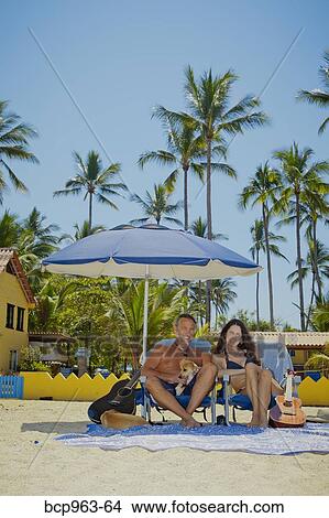 Picture - Happy man and woman in beach chairs with guitars and dogs. Fotosearch