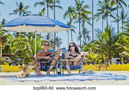 Happy man and woman in beach chairs with guitars and dogs View Large Photo Image Stock Image - Happy man and woman in beach chairs with guitars and dogs. Fotosearch