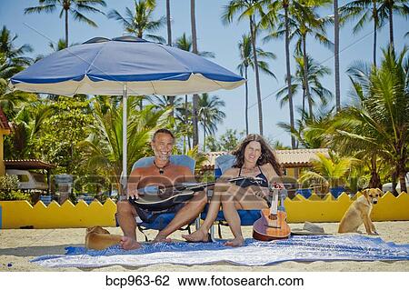 Happy man and woman in beach chairs with guitars and dogs View Large Photo Image Stock Image - Happy man and woman in beach chairs with guitars and dogs. Fotosearch