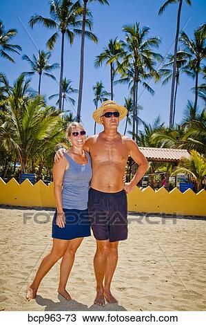 Man and woman arm in arm on beach near palm trees View Large Photo Image Stock Image - Man and woman arm in arm on beach near palm trees. Fotosearch
