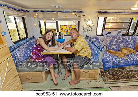 Stock Image - Man and woman holding hands at camper table. Fotosearch