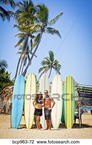 Man and woman in swimsuits in front of row of surfboards View Large Photo Image Stock Image - Man and woman in swimsuits in front of row of surfboards. Fotosearch