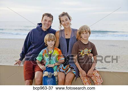 Stock Photo - Man and woman with two boys on beach boardwalk. Fotosearch