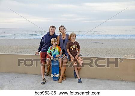 Stock Photograph - Man and woman with two boys on beach boardwalk. Fotosearch