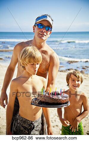 Man holding birthday cake on beach with two boys View Large Photo Image Stock Photograph - Man holding birthday cake on beach with two boys. Fotosearch