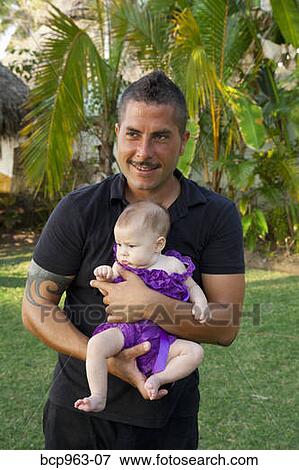 Stock Photo - Man in black clothing holding baby girl. Fotosearch