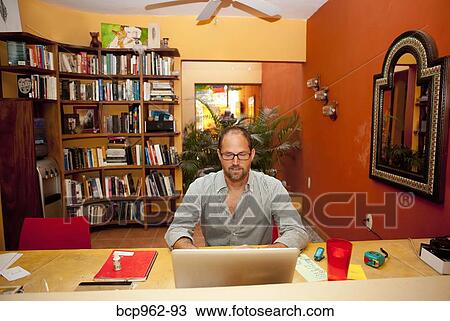 Man seated at desk in home office View Large Photo Image Stock Image - Man seated at desk in home office. Fotosearch