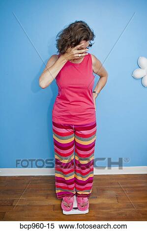 Nervous woman standing on scales View Large Photo Image Stock Photography - Nervous woman standing on scales. Fotosearch