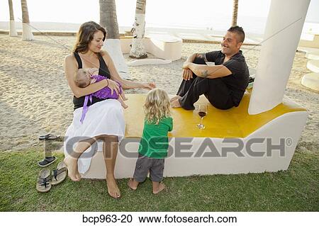 Stock Image - Portrait of young family in beach side park. Fotosearch