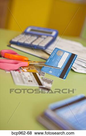 Stock Photo - Scissors cutting up credit cards. Fotosearch