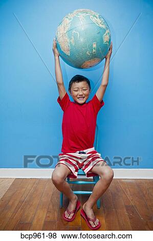 Stock Photo - Seated boy holding globe. Fotosearch