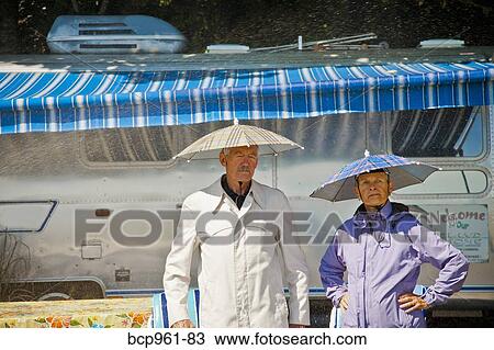 Senior couple in rain hats near airstream camper View Large Photo Image Stock Image - Senior couple in rain hats near airstream camper. Fotosearch