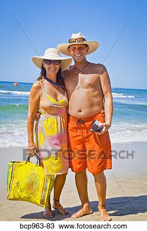 Smiling man and woman arm in arm on beach View Large Photo Image Stock Image - Smiling man and woman arm in arm on beach. Fotosearch