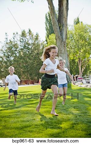 Stock Image - Three young children running in park. Fotosearch