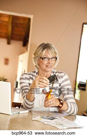 Stock Image - Woman at home office cutting up credit cards. Fotosearch