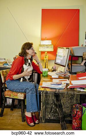 Stock Image - Woman at home office desk with dog. Fotosearch