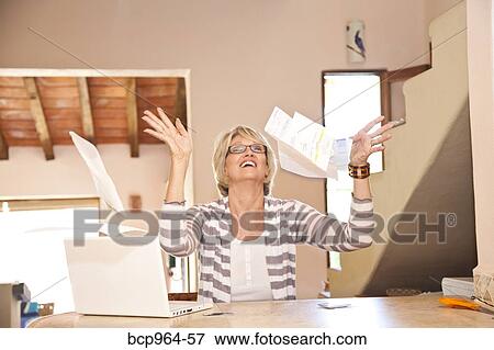 Woman at home office throwing bills in air View Large Photo Image Stock Photo - Woman at home office throwing bills in air. Fotosearch